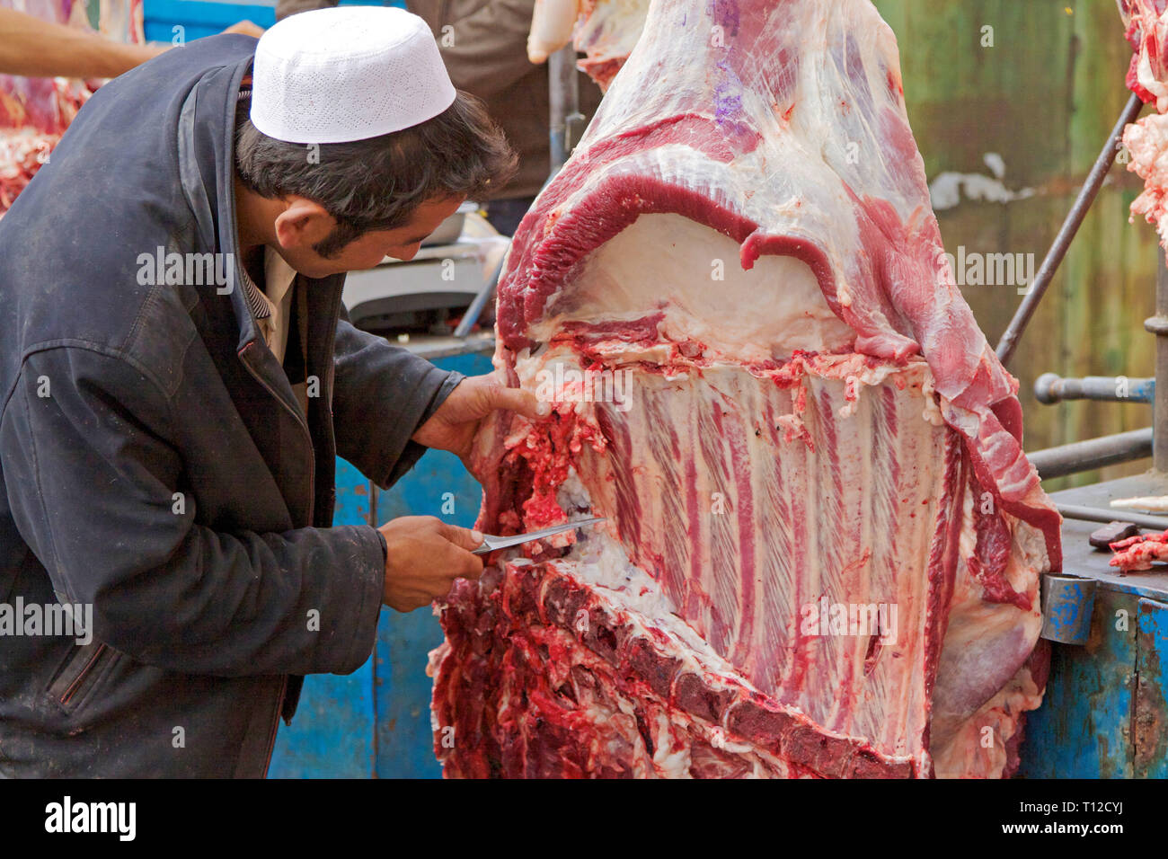 Uighur macellaio di carne da taglio, famoso mercato domenicale a Kashgar, regione autonoma di Xinjiang, Cina. Foto Stock