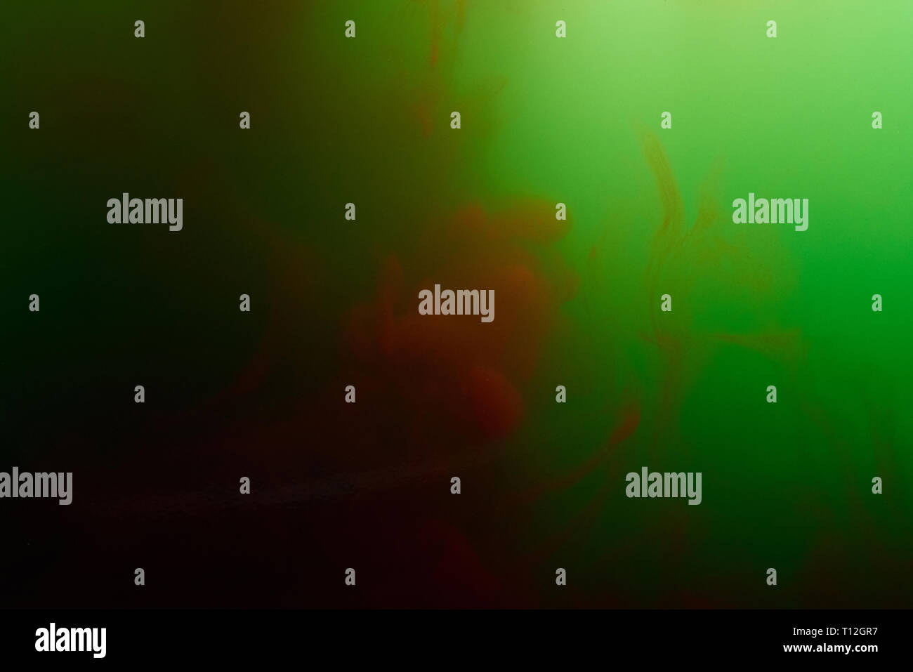 Inchiostro colorato mescolare in acqua. Rosso e verde schizzi di inchiostro close up Foto Stock