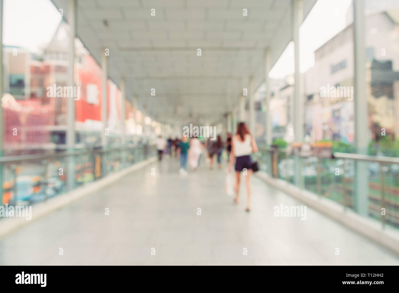 Sfocare lo sfondo immagine della gente che cammina su skywalk nella città, circondato da centri commerciali per lo shopping e gli edifici moderni. Bangkok, Tailandia. Foto Stock
