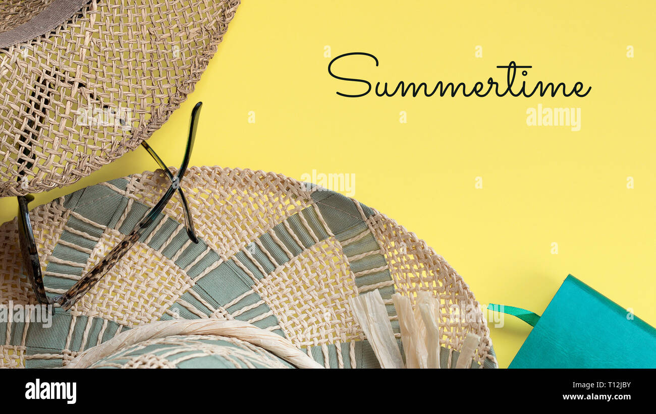 Cappelli di paglia, notebook, occhiali da sole e l'estate del testo in colore giallo brillante background, copia dello spazio. Concetto di estate Foto Stock