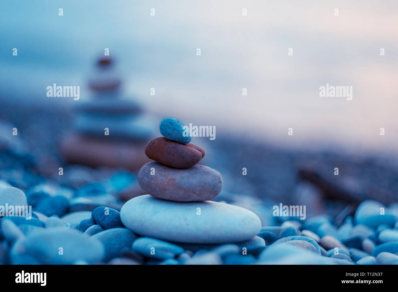 Piramide piegata Zen pietre ghiaia sul mare spiaggia al tramonto Foto Stock