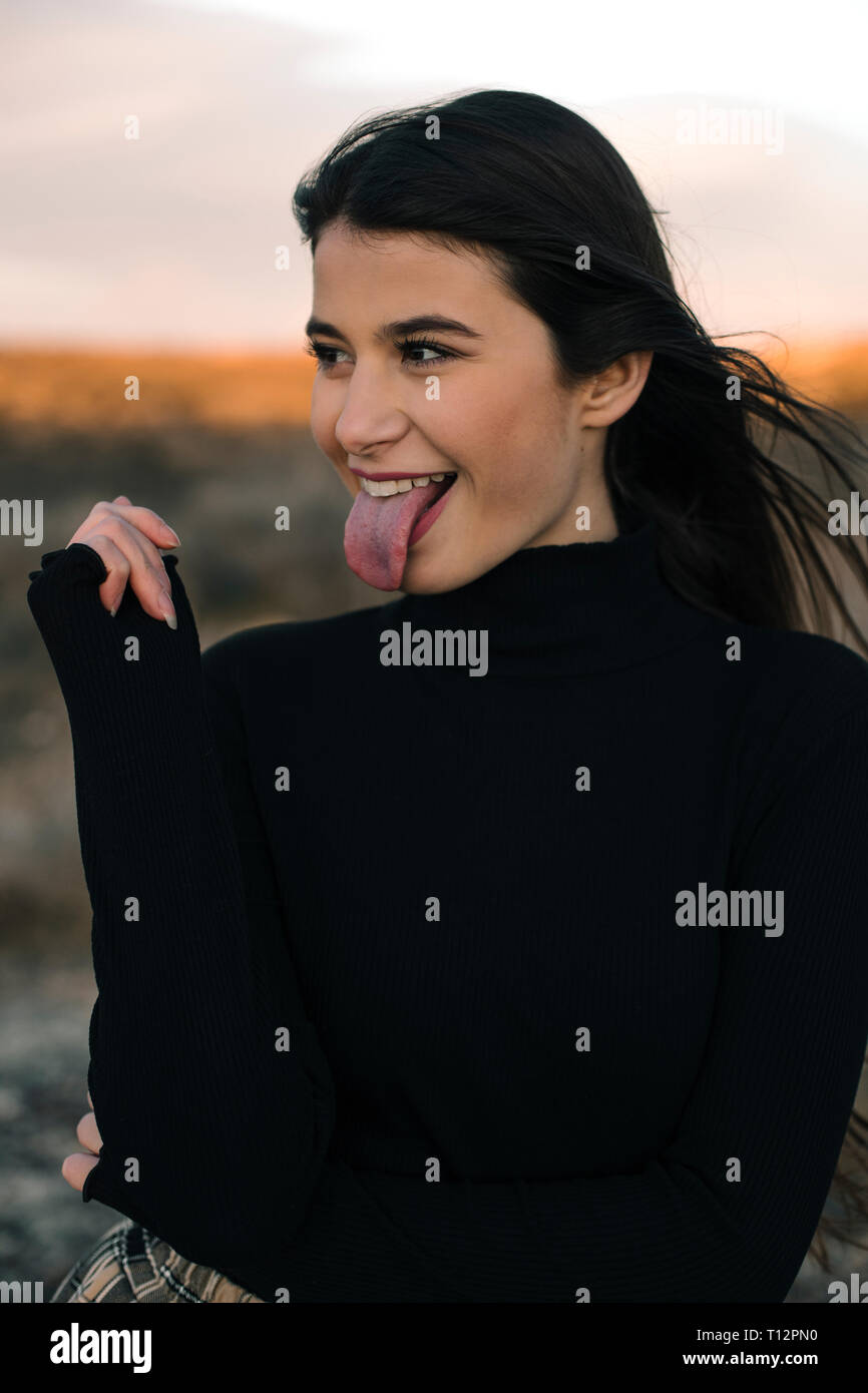 Ritratto di ragazza vestita di nero pullover spuntavano lingua Foto Stock