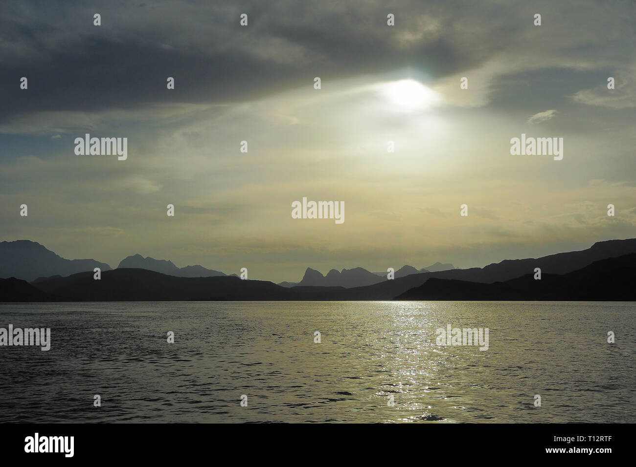 Sun sullo sfondo di montagne e il mare. I Fiordi della penisola di Musandam. Khasab bay. Oman Foto Stock