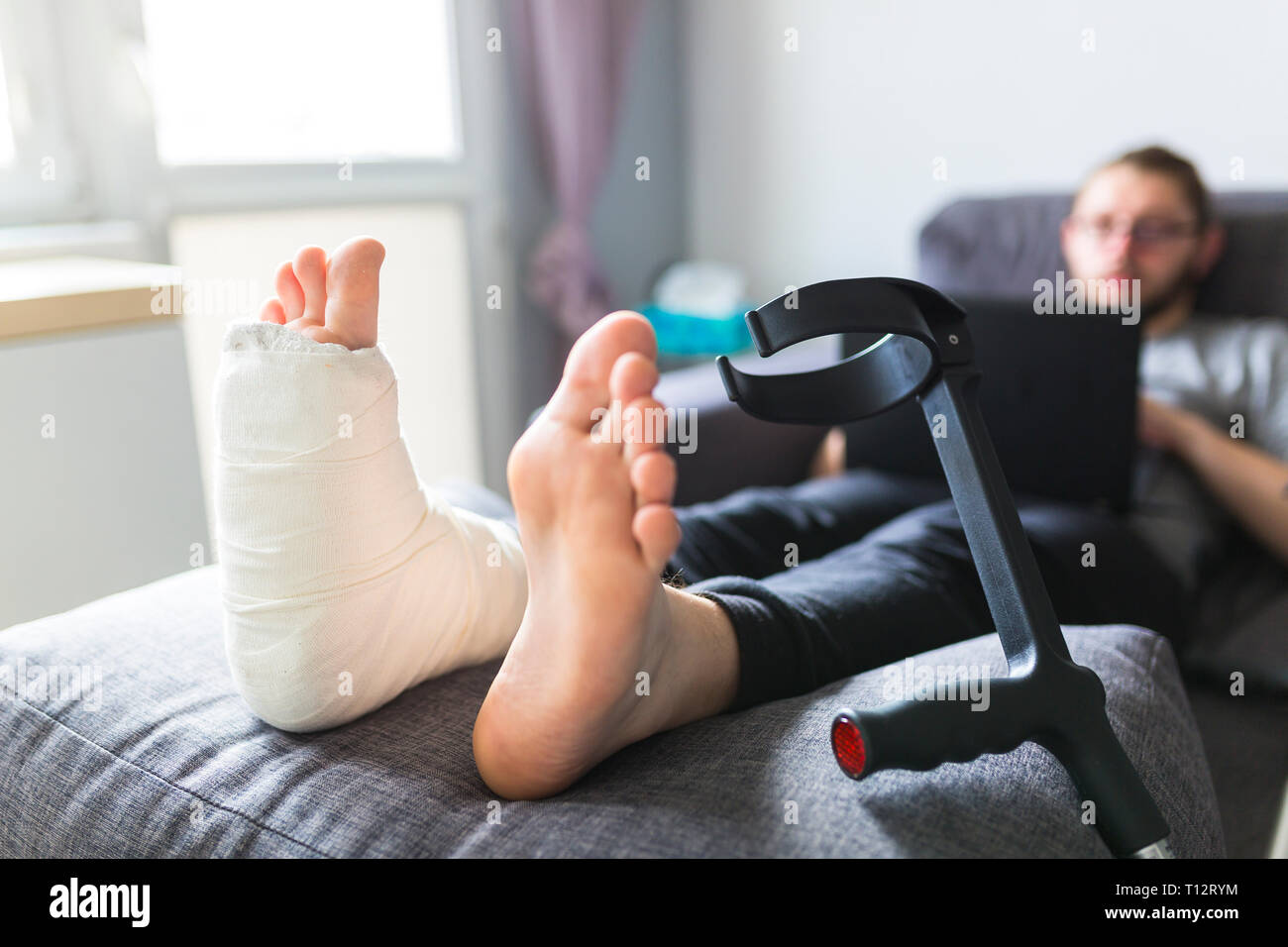 Ragazzo con le stampelle e la gamba rotta a casa Foto Stock