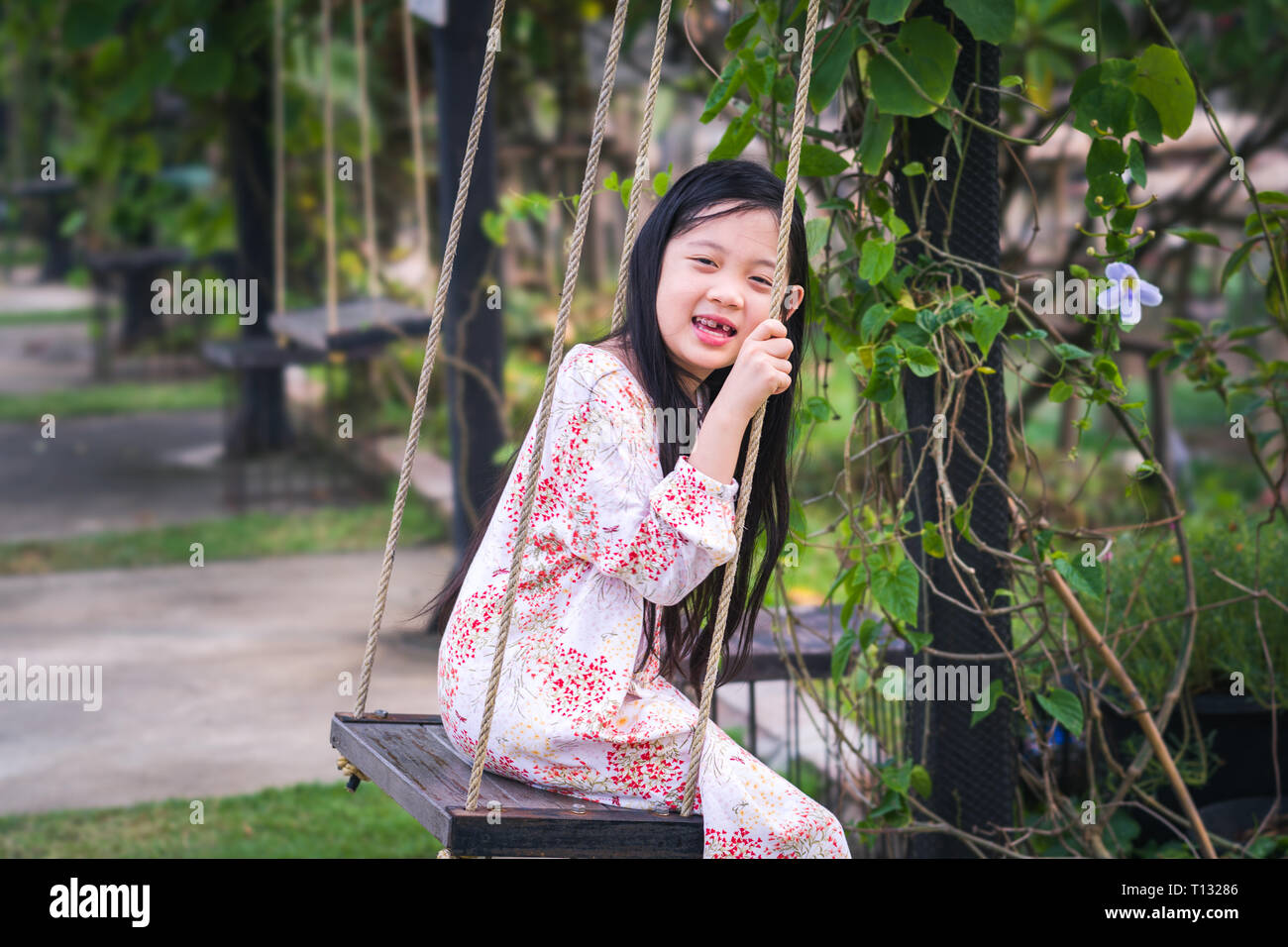 Felice Asian kid riproduzione di oscillare nel parco. Foto Stock