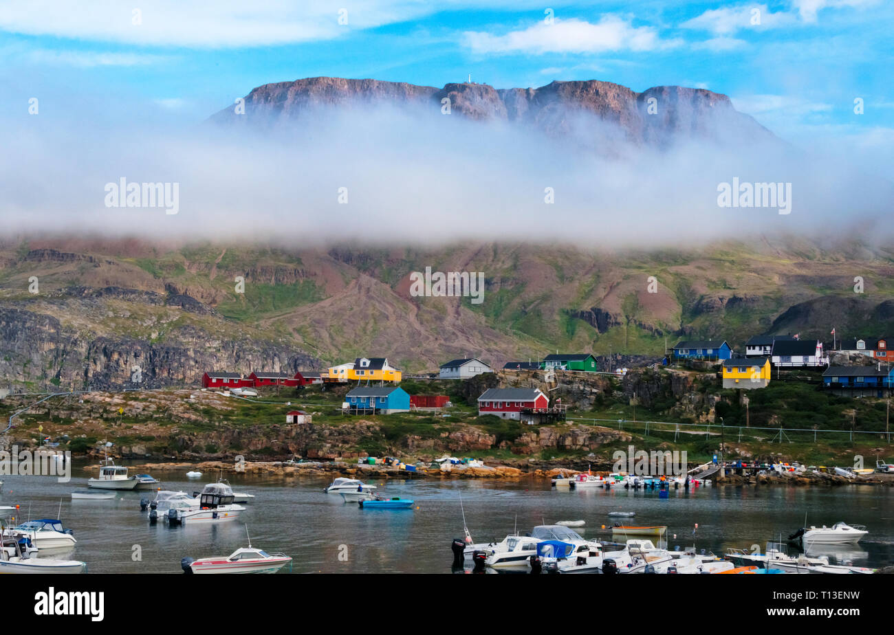 Nebbia pesante sull'isola con dipinto luminosamente case e porto, Qeqertarsuaq, Groenlandia Foto Stock