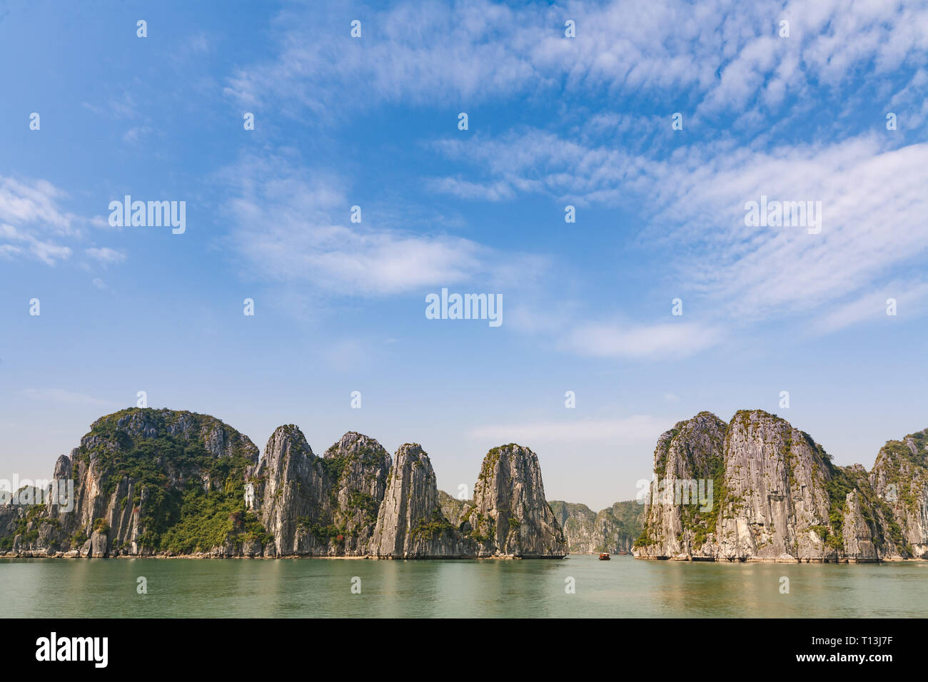 Singolo battello visibile tra alte formazioni carsiche nella baia di Halong Vietnam Foto Stock