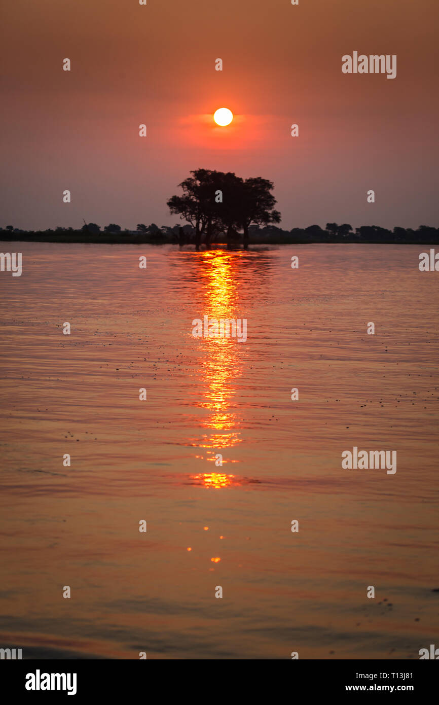Tramonto porta display brillante di colore arancione riflesso del sole che tramonta sul fiume Okavango Delta Foto Stock