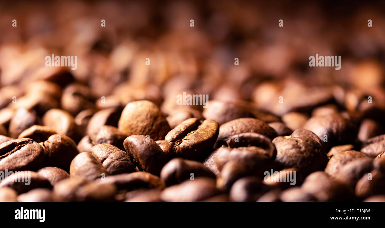 Pila di chicchi di caffè texture, vicino, sfondo scuro, profondità di campo Foto Stock