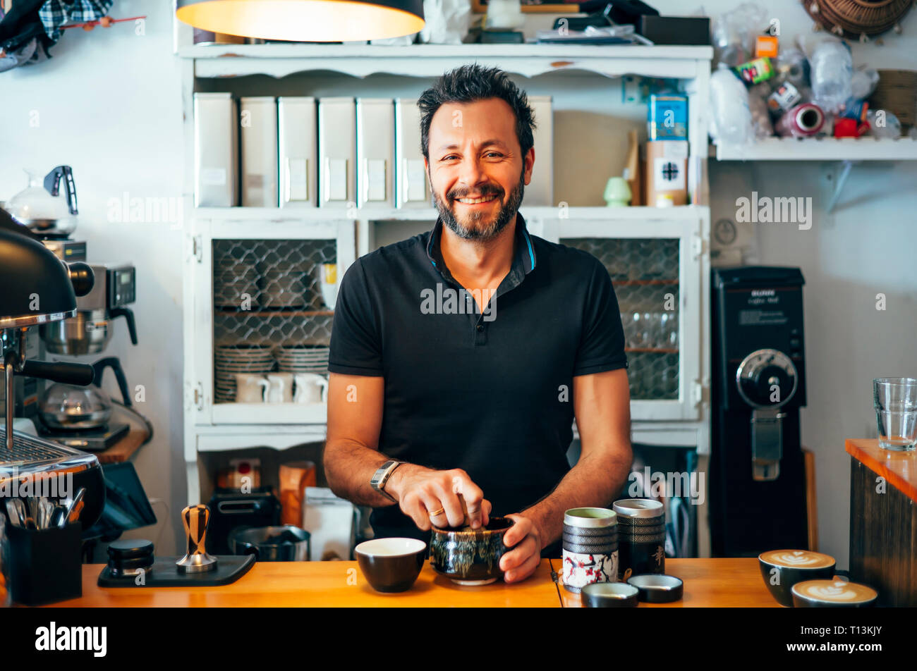 Ritratto di sorridere barista al bancone di un coffee shop Foto Stock