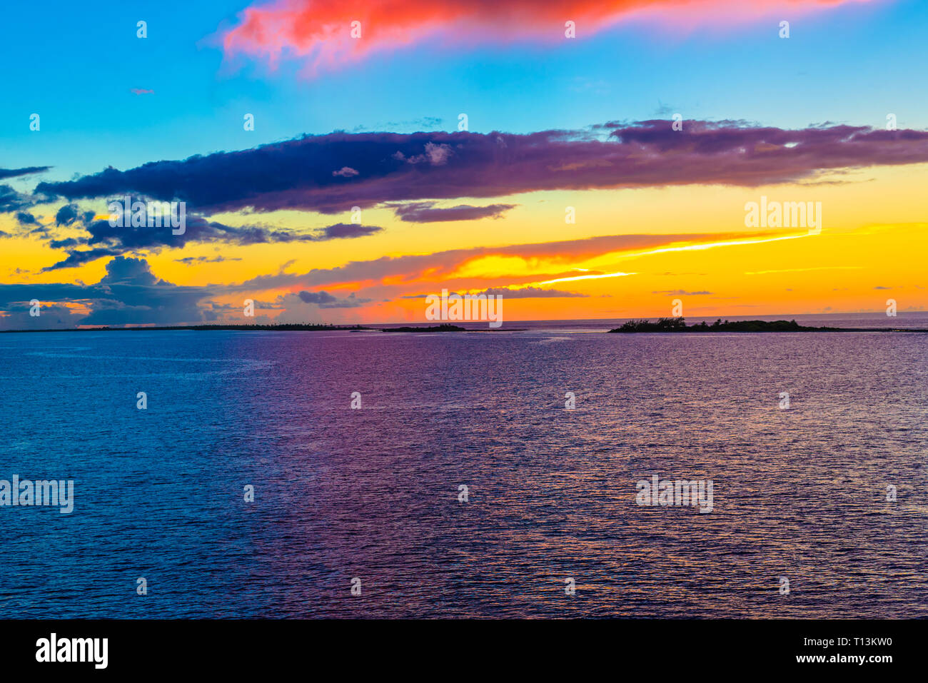 Il cielo diventa arancione e blu su piccole isole nell'Oceano Pacifico al crepuscolo. Foto Stock