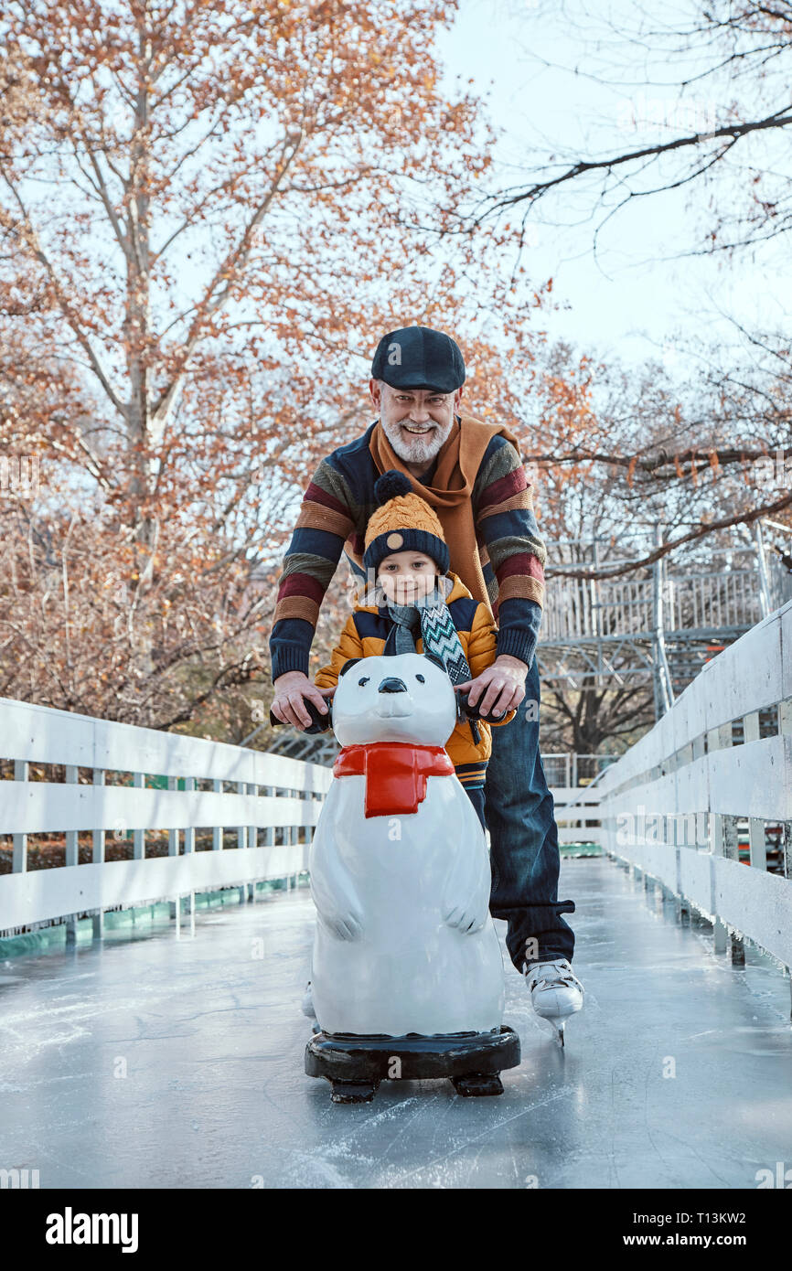 Nonno e nipote sulla pista di pattinaggio su ghiaccio, pattinaggio su ghiaccio, usando ghiaccio bear figura come prop Foto Stock