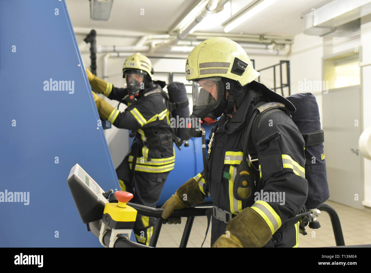 Due vigili del fuoco con respiratore e serbatoio d'aria esercitando in sala esercizi Foto Stock