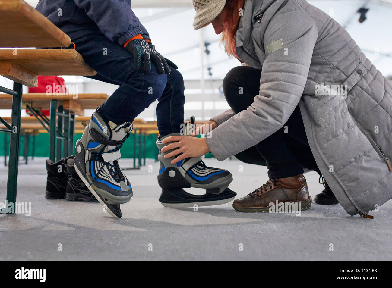Madre aiutare suo figlio a mettere su pattini da ghiaccio Foto Stock