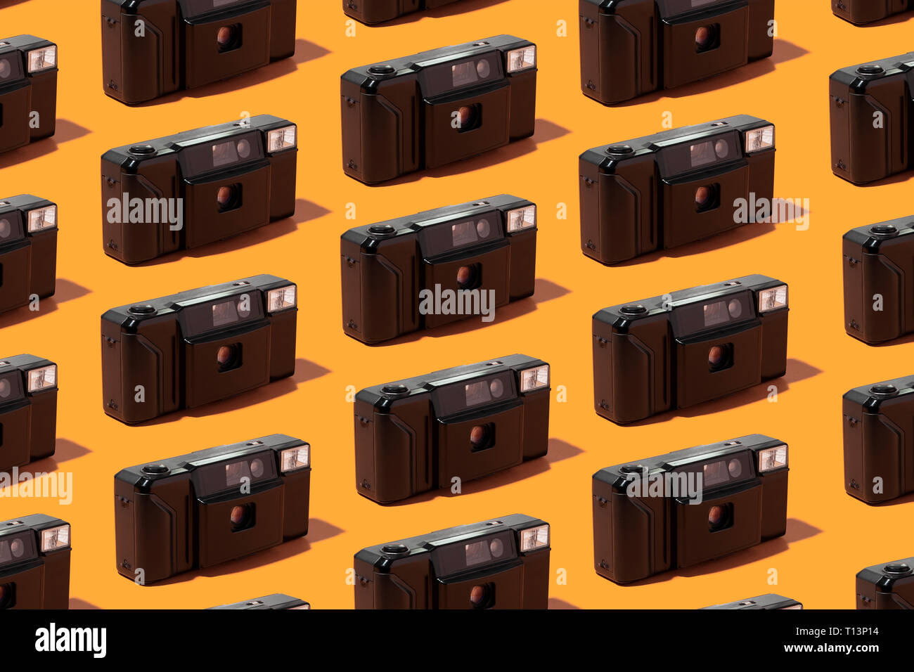 Plastica fotocamere foto organizzate in una fila su sfondo arancione Foto Stock