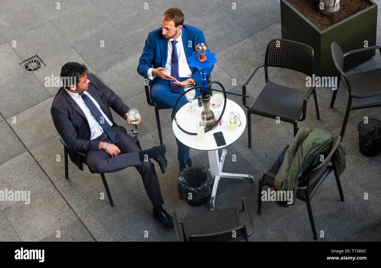 Due giovani uomini d'affari in abiti che bevono un drink in un caffè all'aperto dopo il lavoro a Siviglia Foto Stock