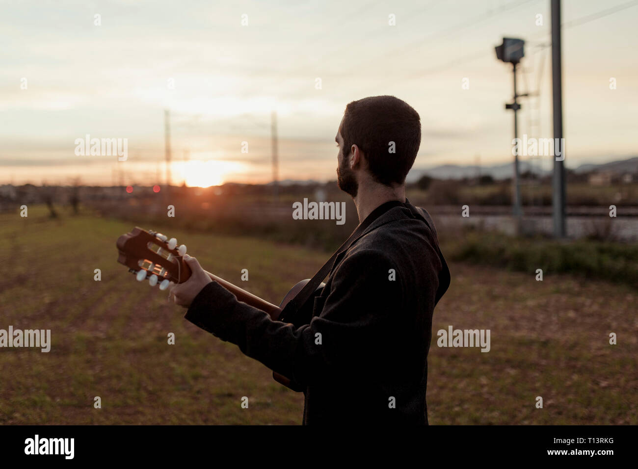 Irriconoscibile musicista maschio a suonare la chitarra al tramonto Foto Stock