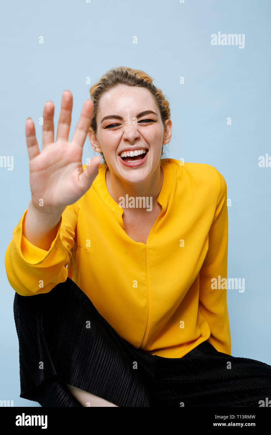 Ritratto di ridere giovane donna indossa camicetta gialla davanti a sfondo blu Foto Stock