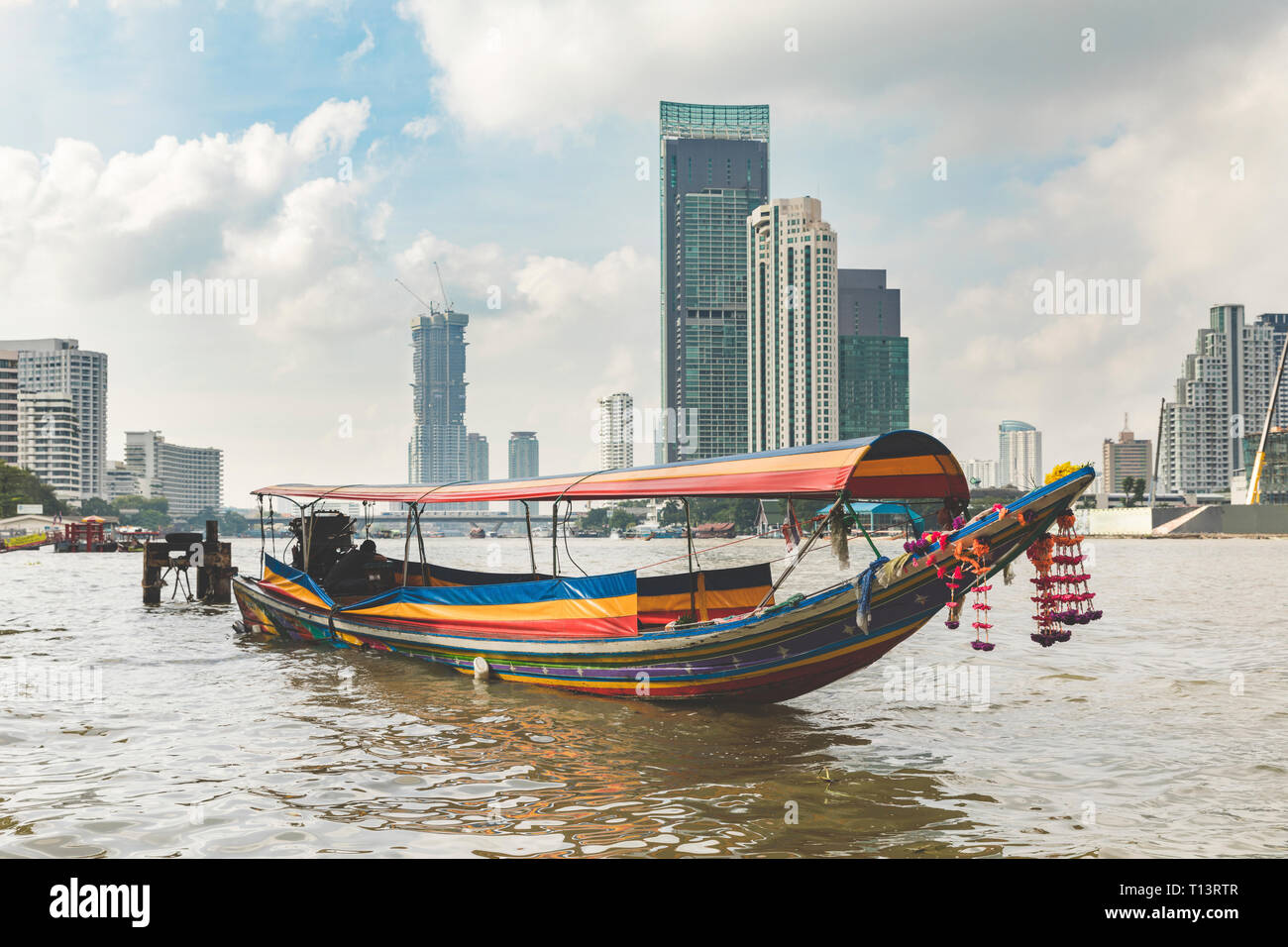 Thailandia, Bangkok, tipica barca sul fiume Chao Phraya con la città di grattacieli in background Foto Stock