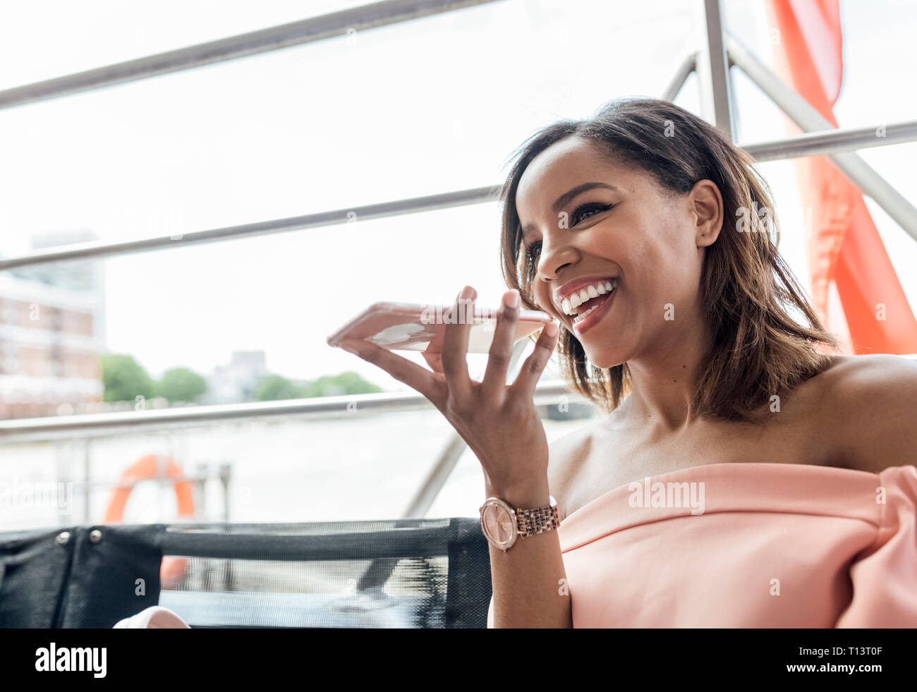 UK, Londra, felice bella donna utilizzando il telefono cellulare mentre si è in viaggio in battello sul fiume Tamigi Foto Stock