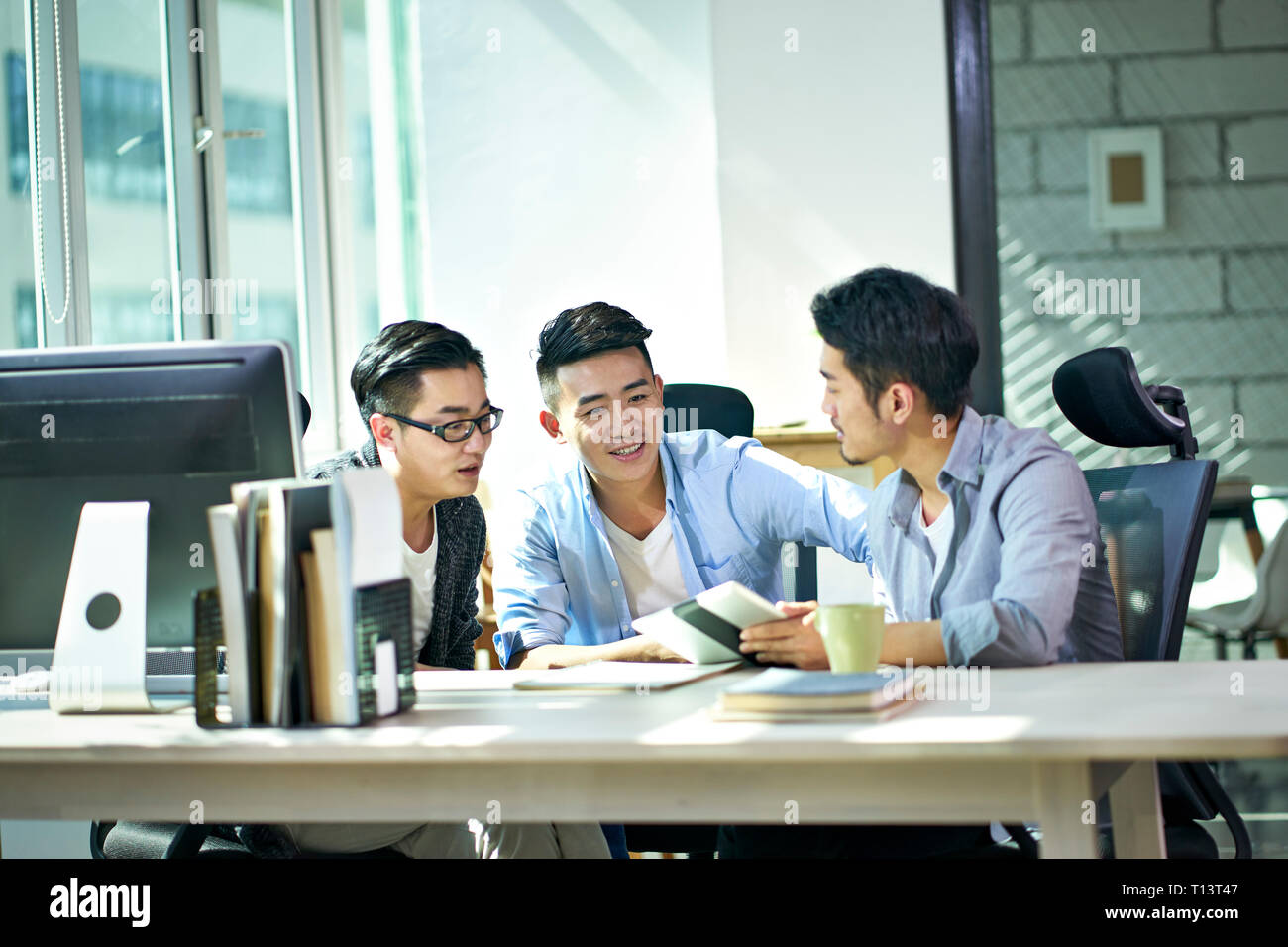 Tre giovani asiatici dirigenti aziendali che lavorano insieme a discutere di business plan in ufficio. Foto Stock