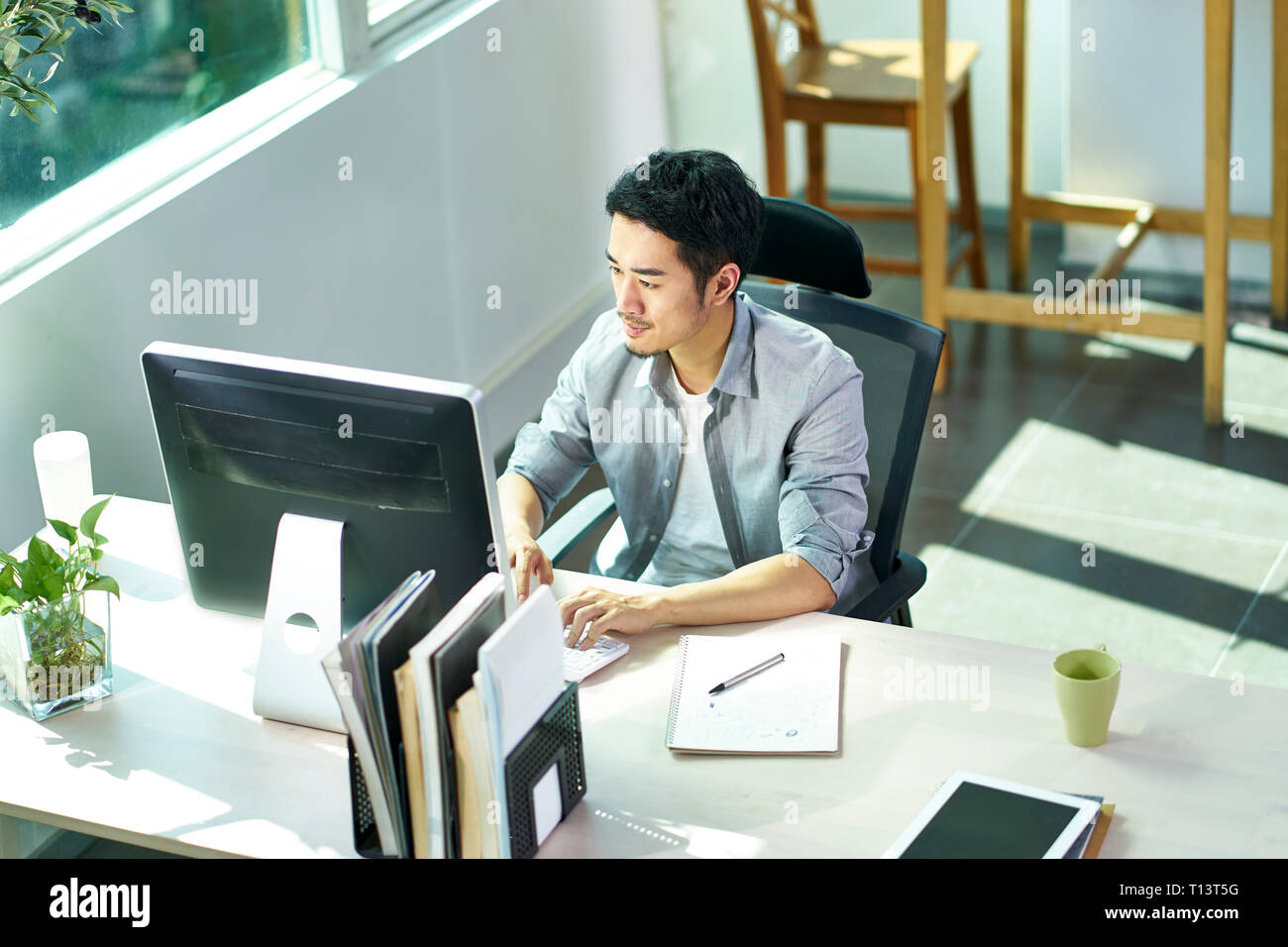Angolo di alta vista di giovani asian business persona che lavora in ufficio tramite il computer desktop Foto Stock
