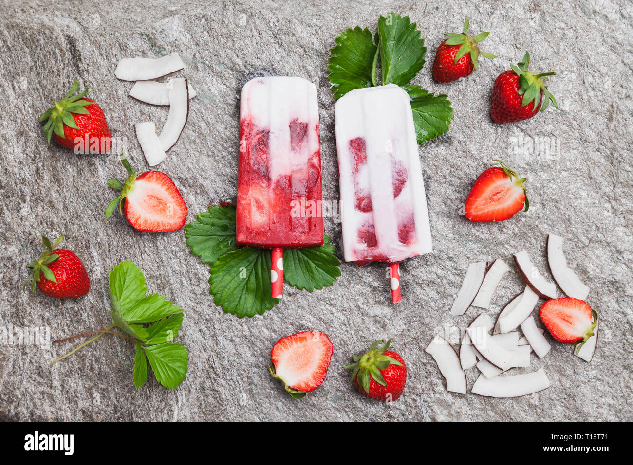 In casa di cocco fragola ghiaccioli con fragole fresche e fette di noce di cocco sul granito Foto Stock