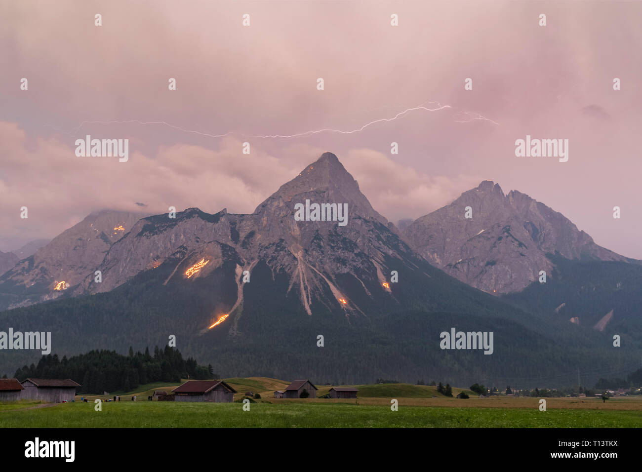 Austria, Lermoos, Ehrwalder Becken, Ehrwalder Sonnenspitze con midsummer fire, Gruenstein, Ehrwald, Mieminger Kette con temporale e fulmini Foto Stock