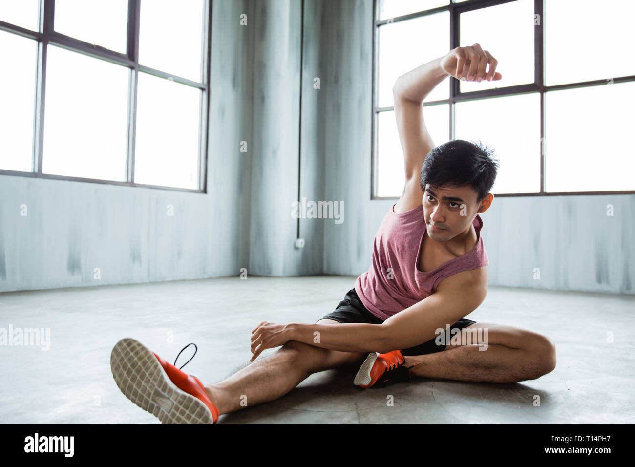 Asian giovane uomo facendo stretching addominali prima di allenamento Foto Stock