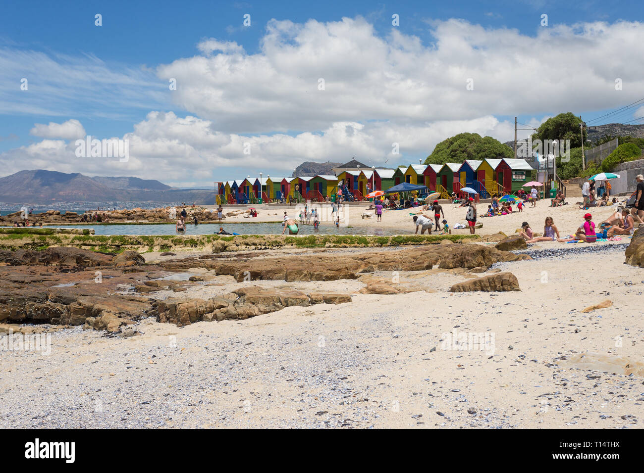 Pittoresca spiaggia di capanne a St James spiaggia e piscina di marea con persone godendo il sole estivo e lo stile di vita di vacanze Penisola del Capo, Cape Town, Sud Africa Foto Stock