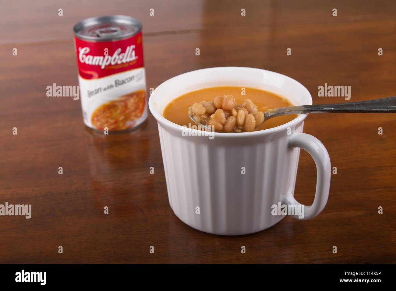 Un bianco tazza di fagioli e pancetta zuppa su una tavola di legno con il possibile in background Foto Stock