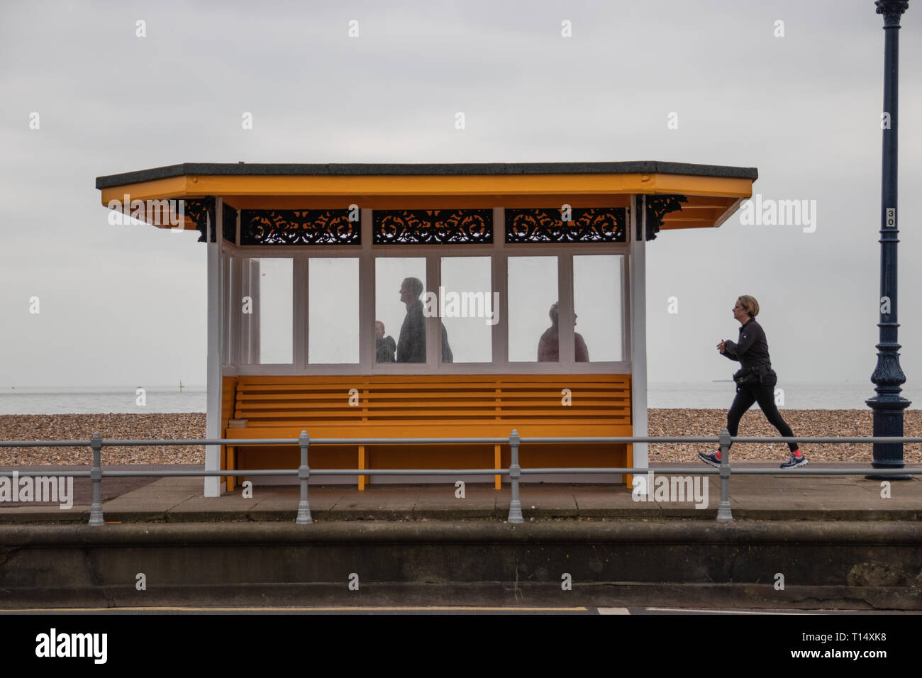 La gente si fermò in una spiaggia un rifugio con pareggiatore passando da Southsea, Regno Unito Foto Stock