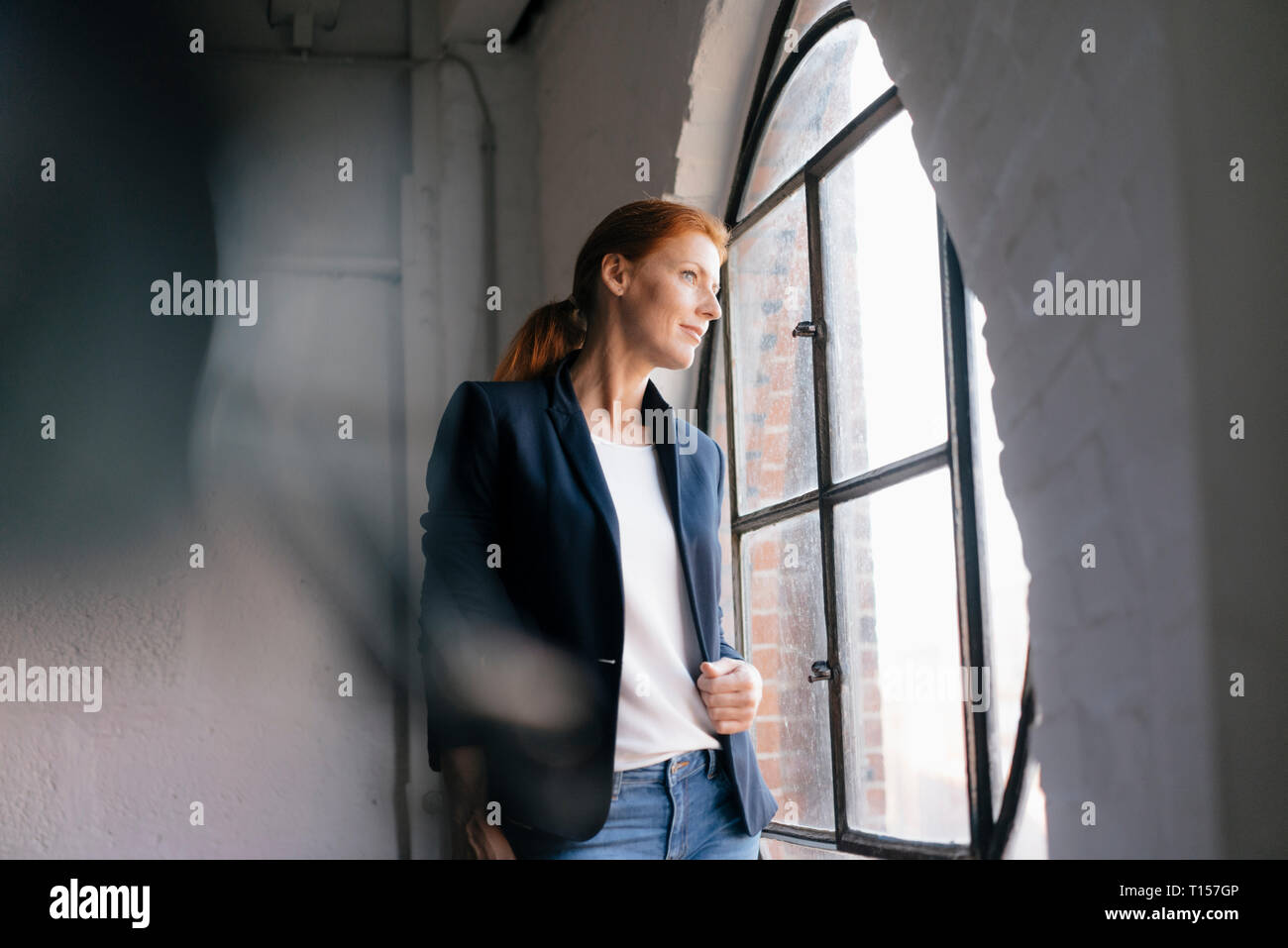 Imprenditrice guardando fuori della finestra Foto Stock