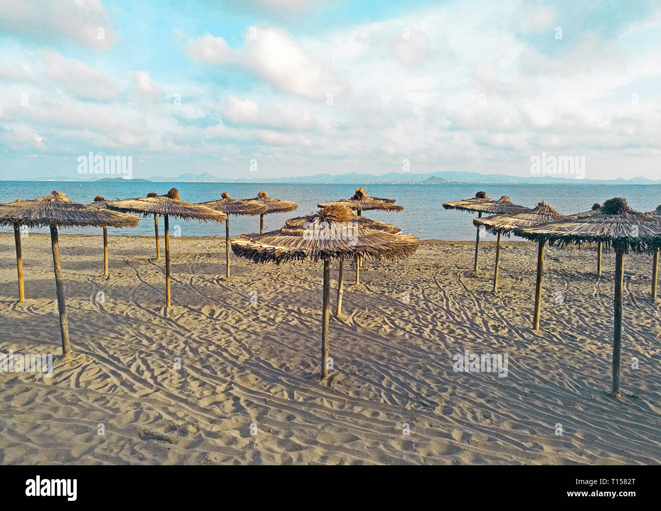 Coperti di paglia ombrellone sulla spiaggia con acqua turchese a sfondo Foto Stock