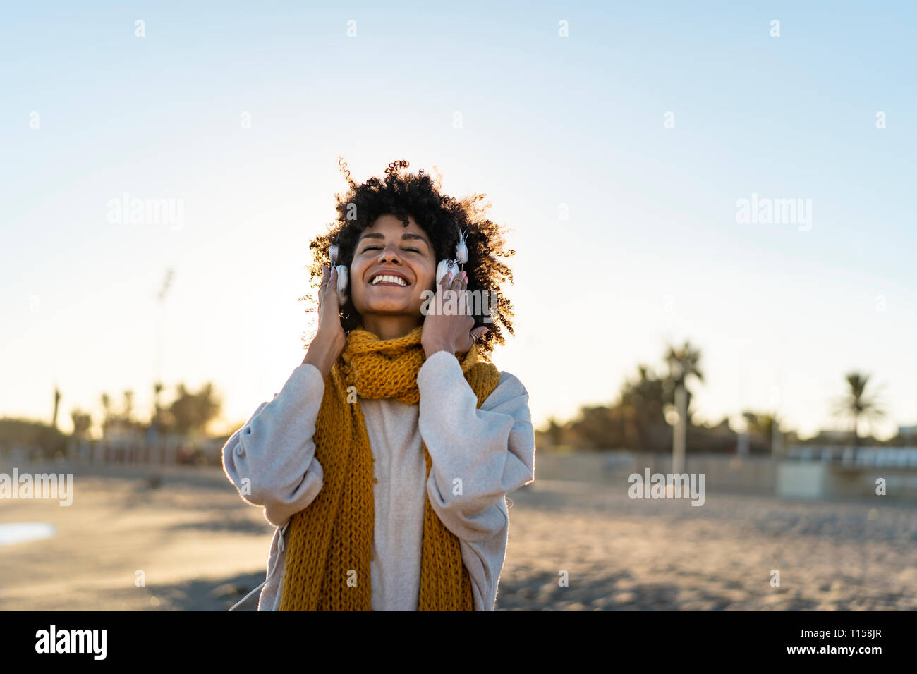 Donna con foulard giallo, ascolto di musica in spiaggia Foto Stock