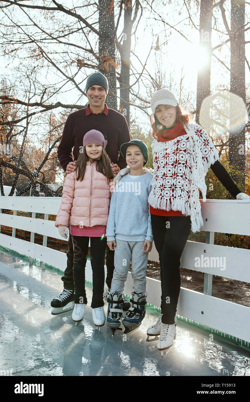 Famiglia appoggiata sulla ringhiera presso la pista di pattinaggio su ghiaccio Foto Stock
