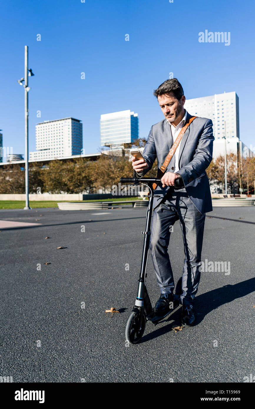 Imprenditore matura il pendolarismo nella città con il suo kick scooter Foto Stock