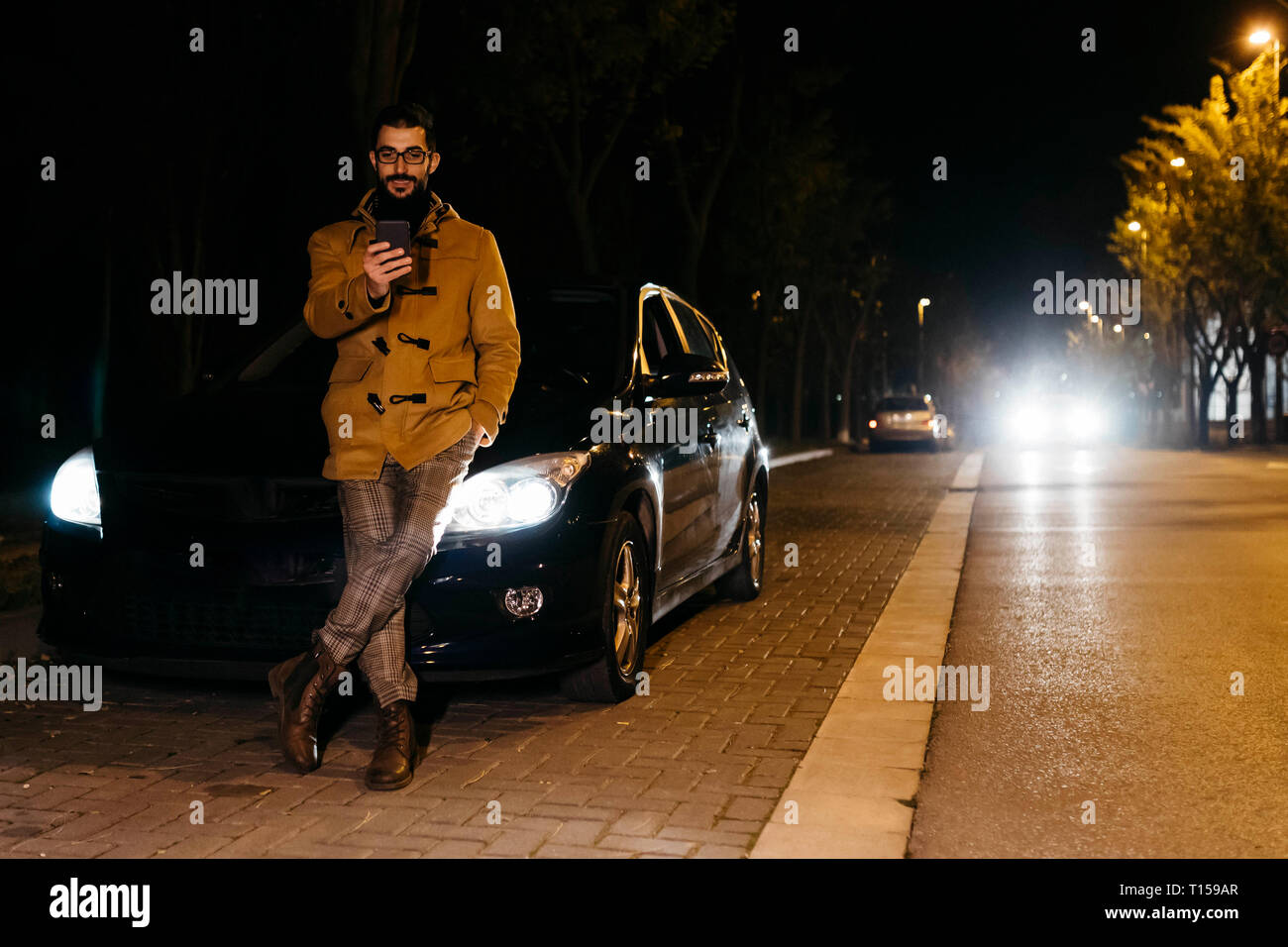 Spagna, Igualada, uomo tramite telefono cellulare al di fuori della macchina di notte Foto Stock