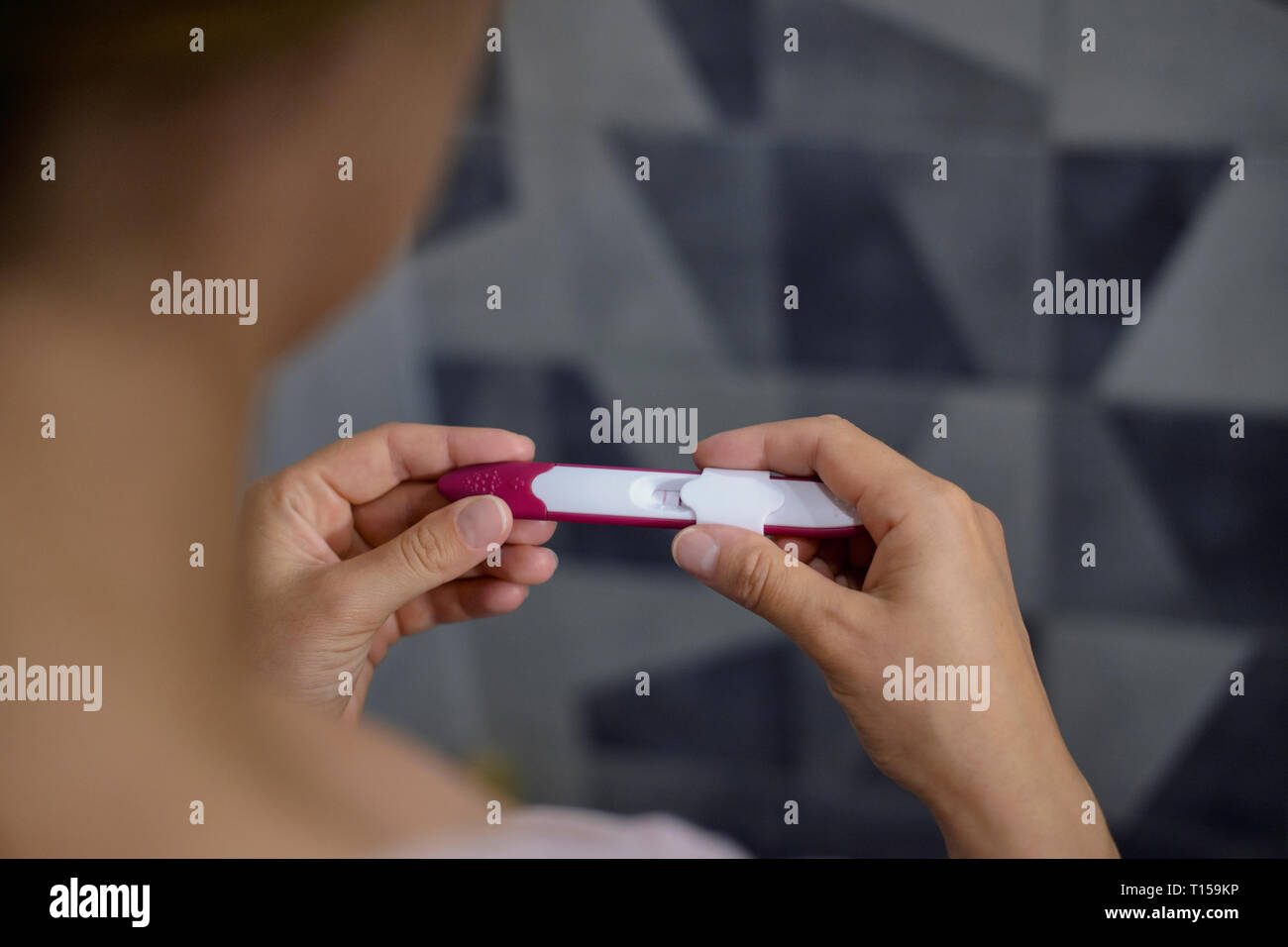 Close-up di donna controllando il suo test di gravidanza positivo mostrando Foto Stock