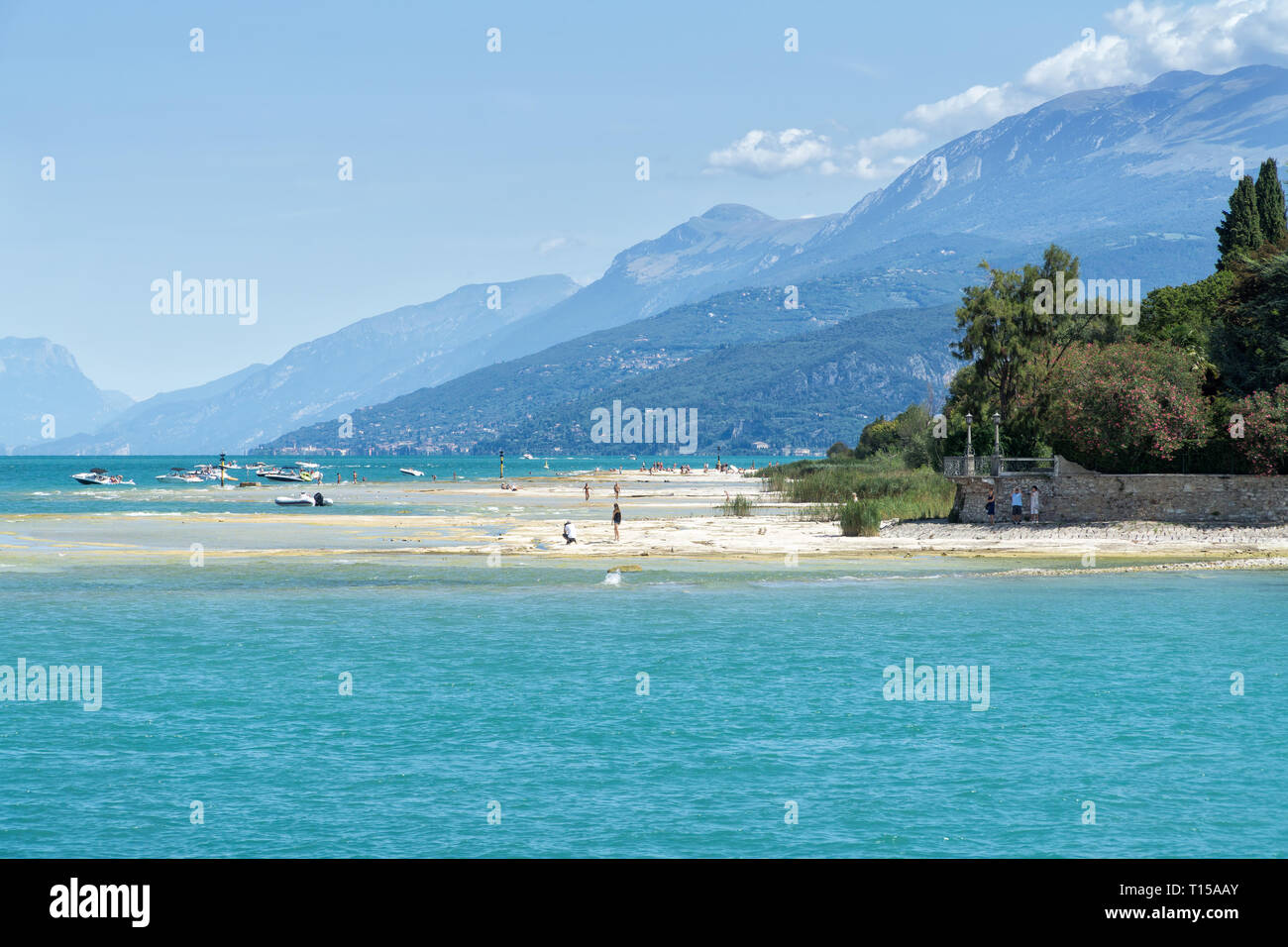 SIRMIONE, Italia - 07 agosto 2017: turisti sulla spiaggia sassosa della cittadina di Sirmione sul Lago di Garda. Vista della costa del lago di Garda. Foto Stock