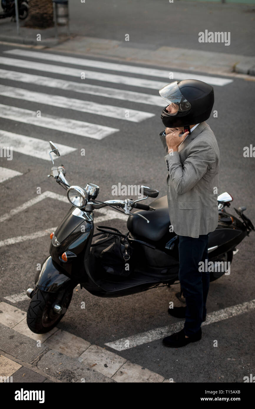 Imprenditore accanto a scooter mettendo sul casco Foto Stock