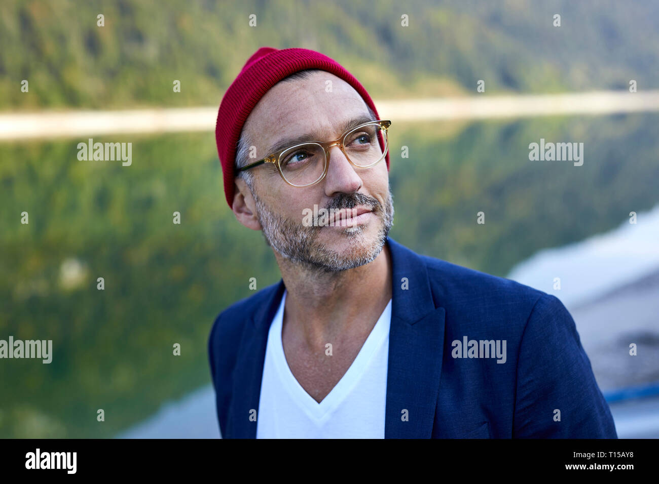 Ritratto di barbuto uomo maturo con gli occhiali e cappuccio rosso in natura Foto Stock