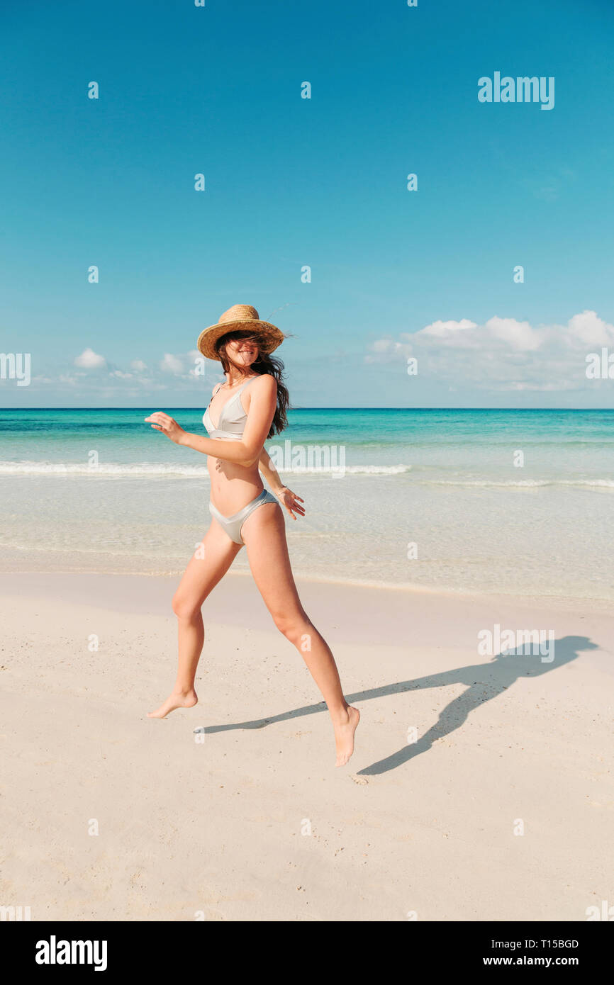 Spagna, Mallorca, Felice giovane donna in vacanza il salto sulla spiaggia durante un giorno di estate Foto Stock