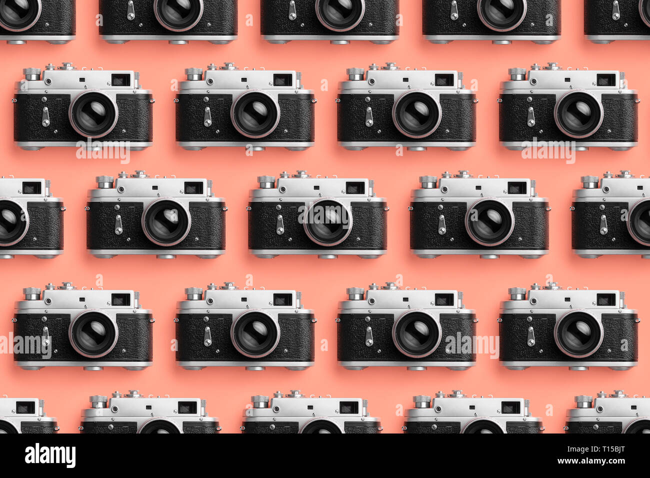 Le macchine fotografiche organizzate in una fila su coral colore di sfondo Foto Stock