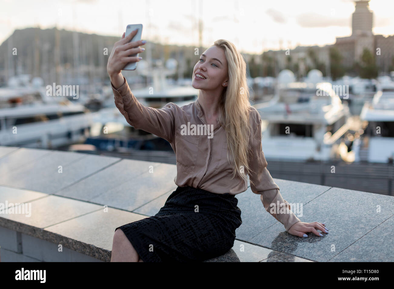 Sorridente giovane donna prendendo un selfie al waterfront Foto Stock