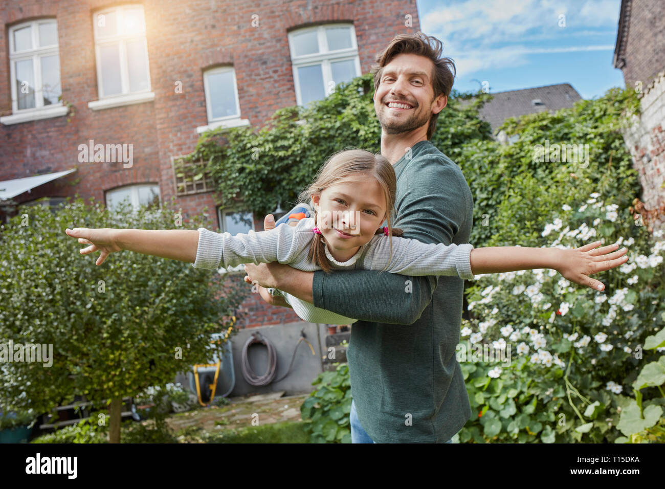 Padre Felice giocando con la figlia nel giardino della loro casa Foto Stock