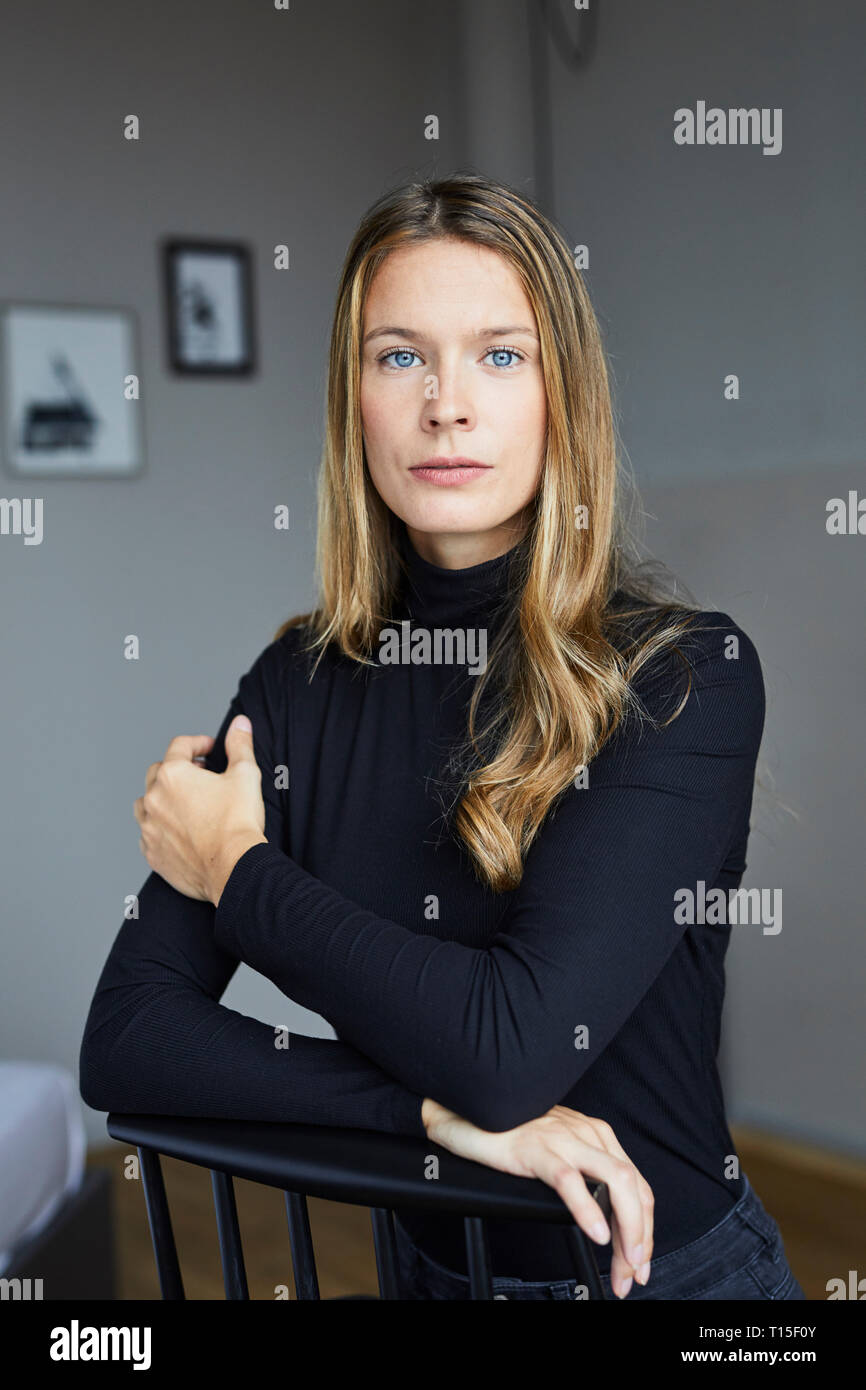 Ritratto di giovane donna vestita di nero turtleneck seduti su una sedia Foto Stock