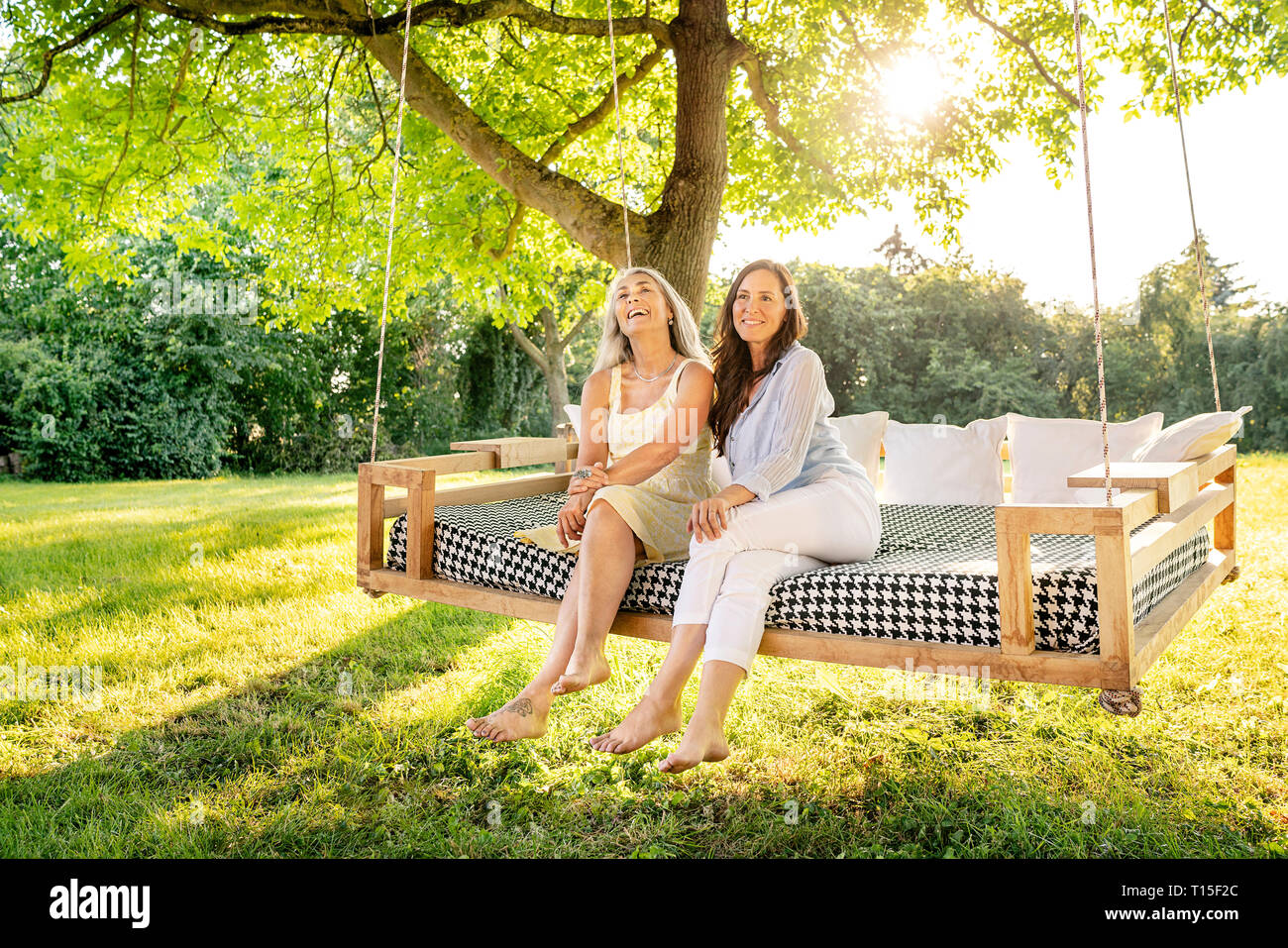 Due donne rilassante su un letto sospeso in giardino Foto Stock