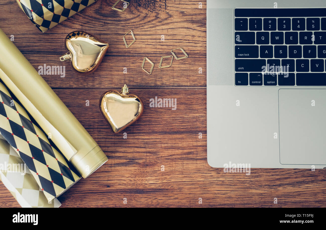 Scrivania da ufficio con computer portatile, la carta di avvolgimento, la graffetta e golden baubles di Natale Foto Stock