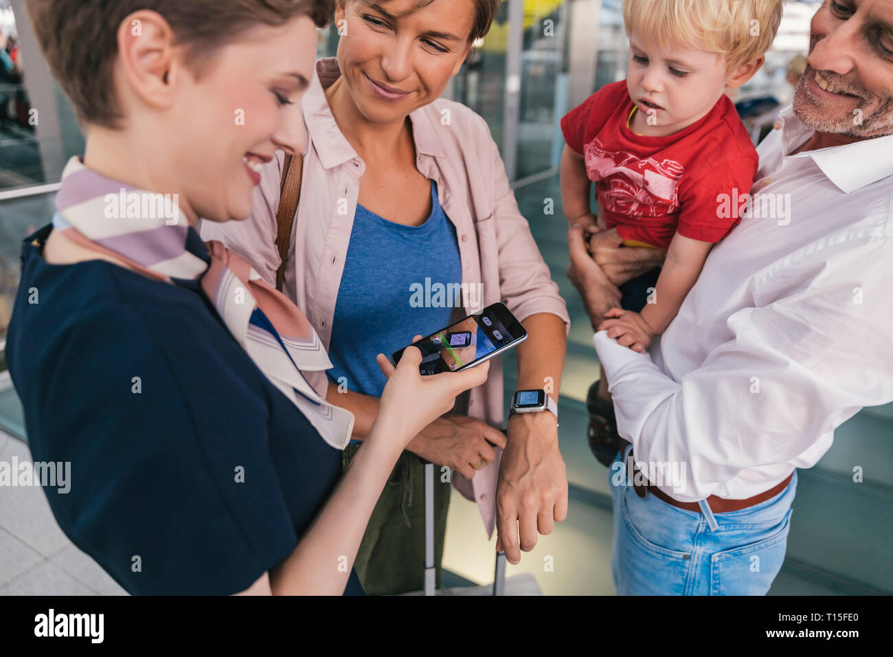 Dipendente della compagnia aerea di scansione dei codici QR di passeggeri con smartwatch in aeroporto Foto Stock